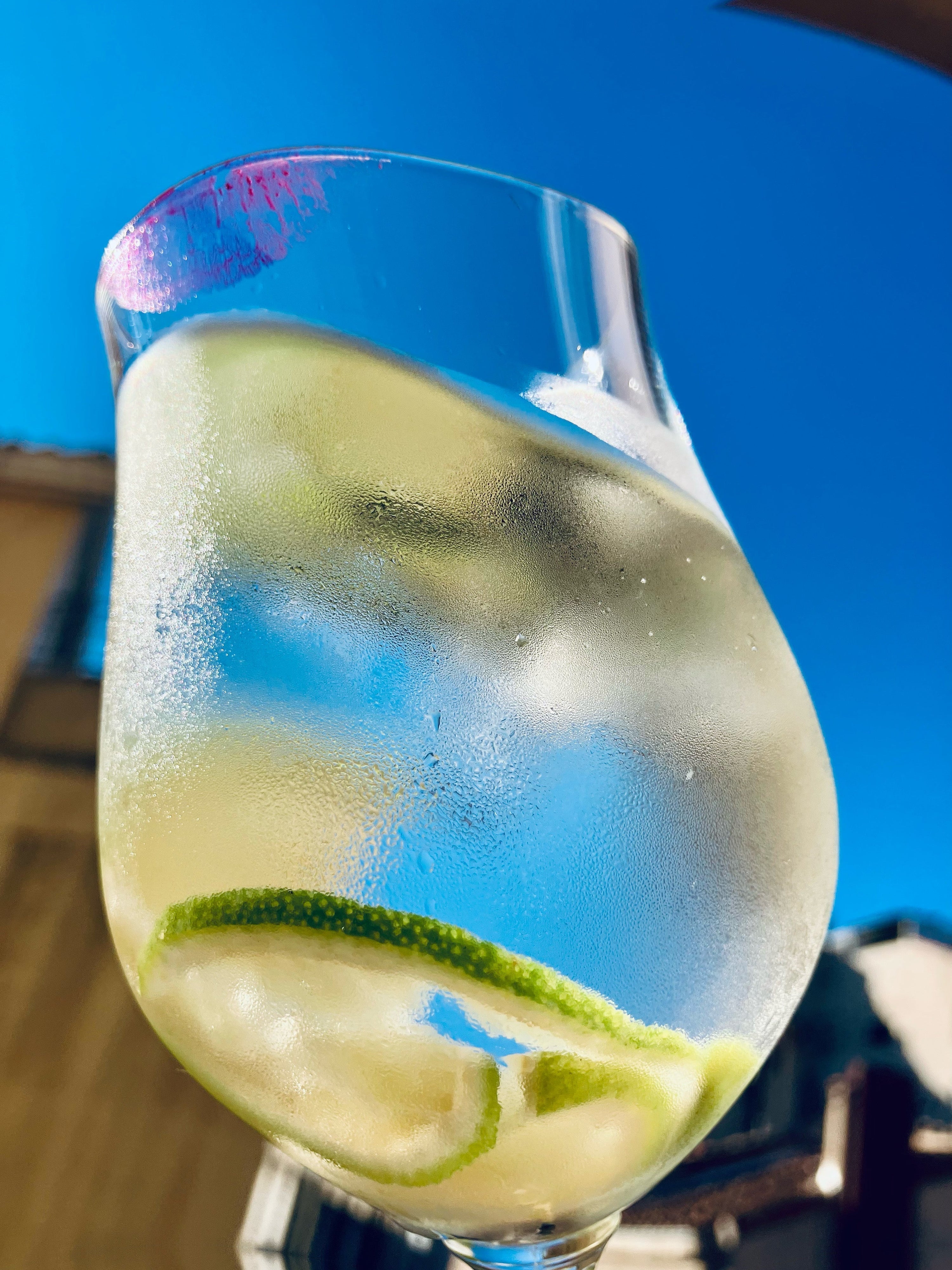 Citrus-infused aromatic water with lime slices in wine glass - living perfume and drinkable fragrance recipe